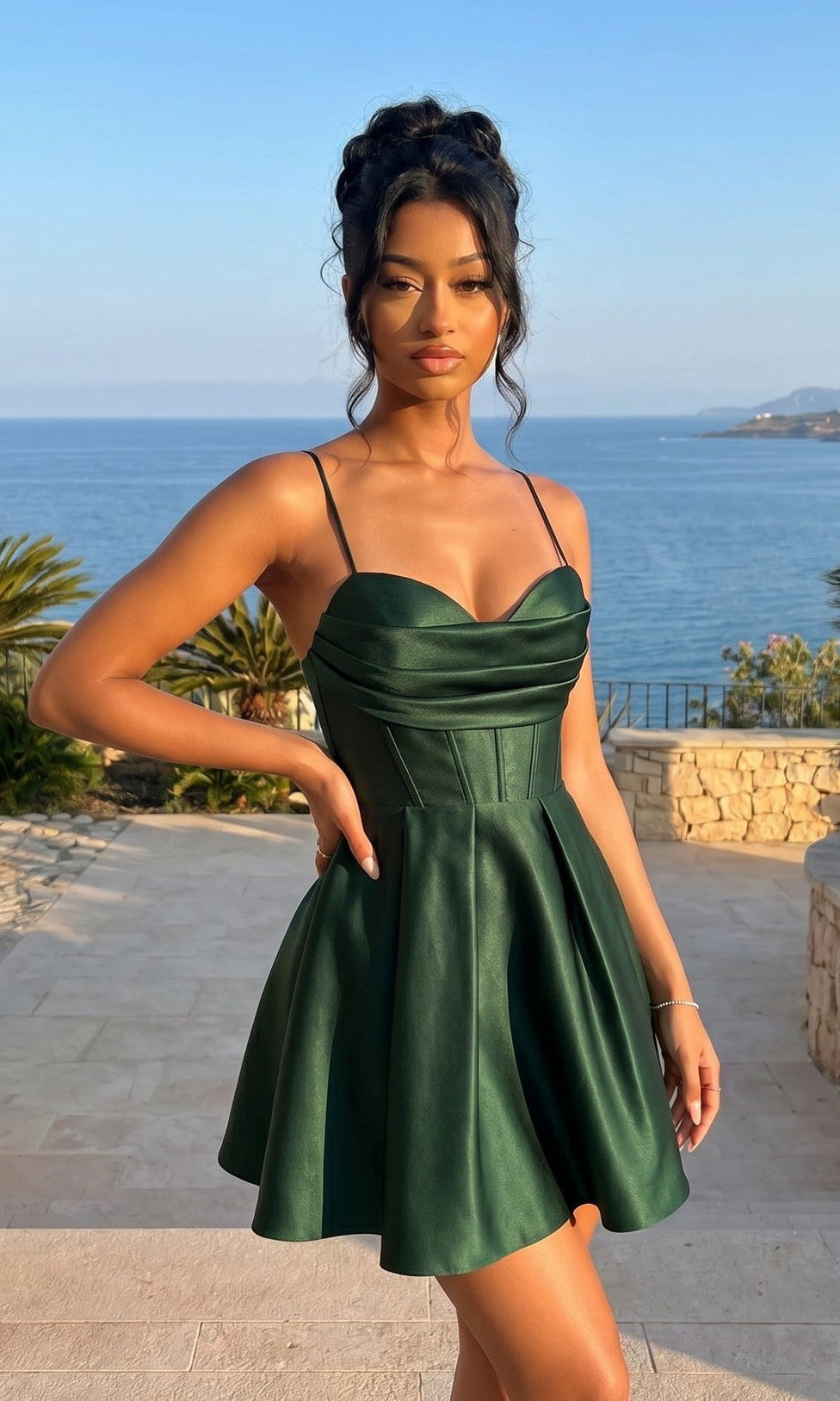 A woman stands outdoors by the ocean and a stone patio, wearing the Lace-Up Short Hoco Dress: Blondie Nites 4578BN in Hunter.